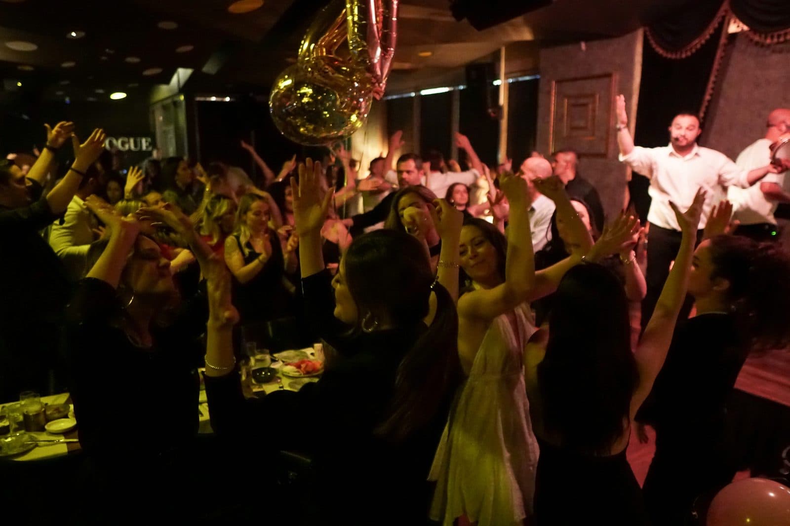 Balonlarla süslenmiş salonda dans eden kalabalık